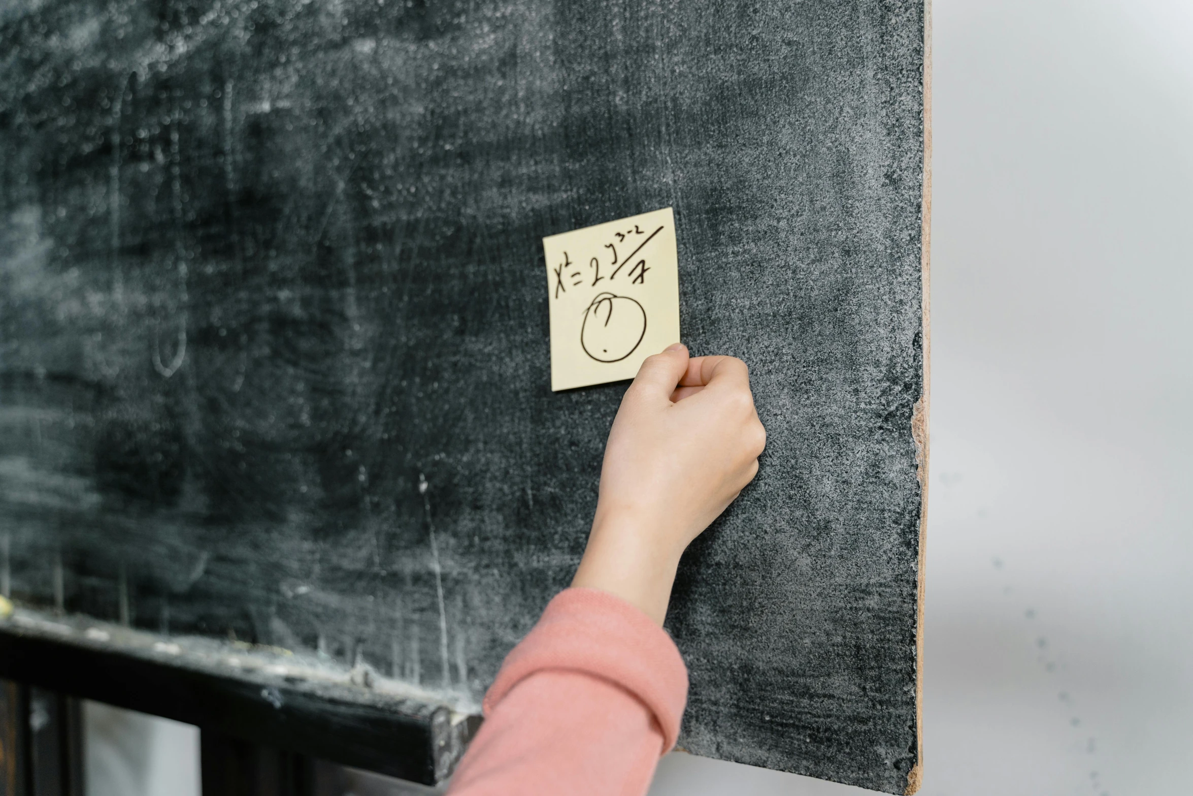 the hand is pressing on the chalkboard that is attached to the wall