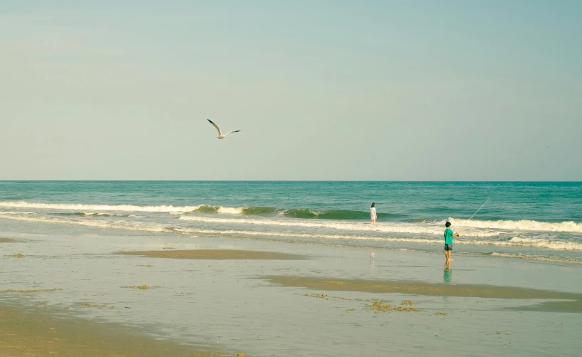 a lone person standing on the beach with water in the background