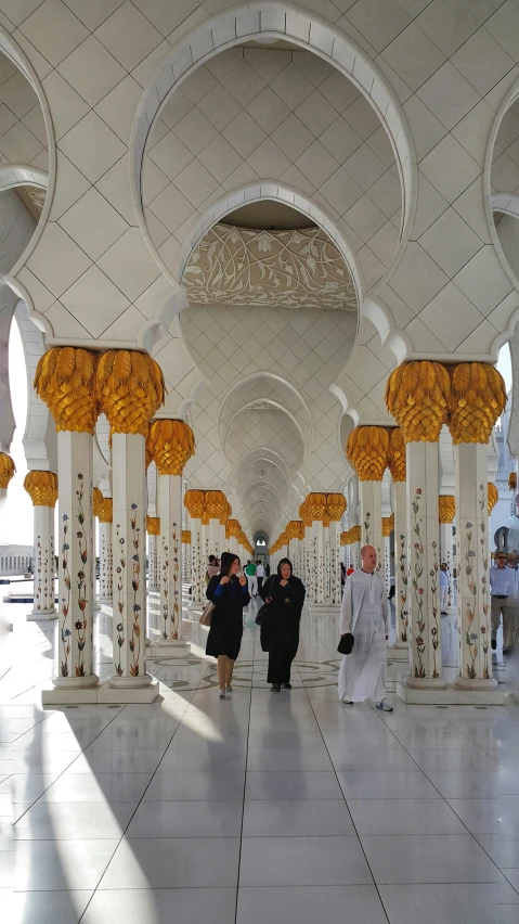 an outdoor lobby with many columns and people walking in it