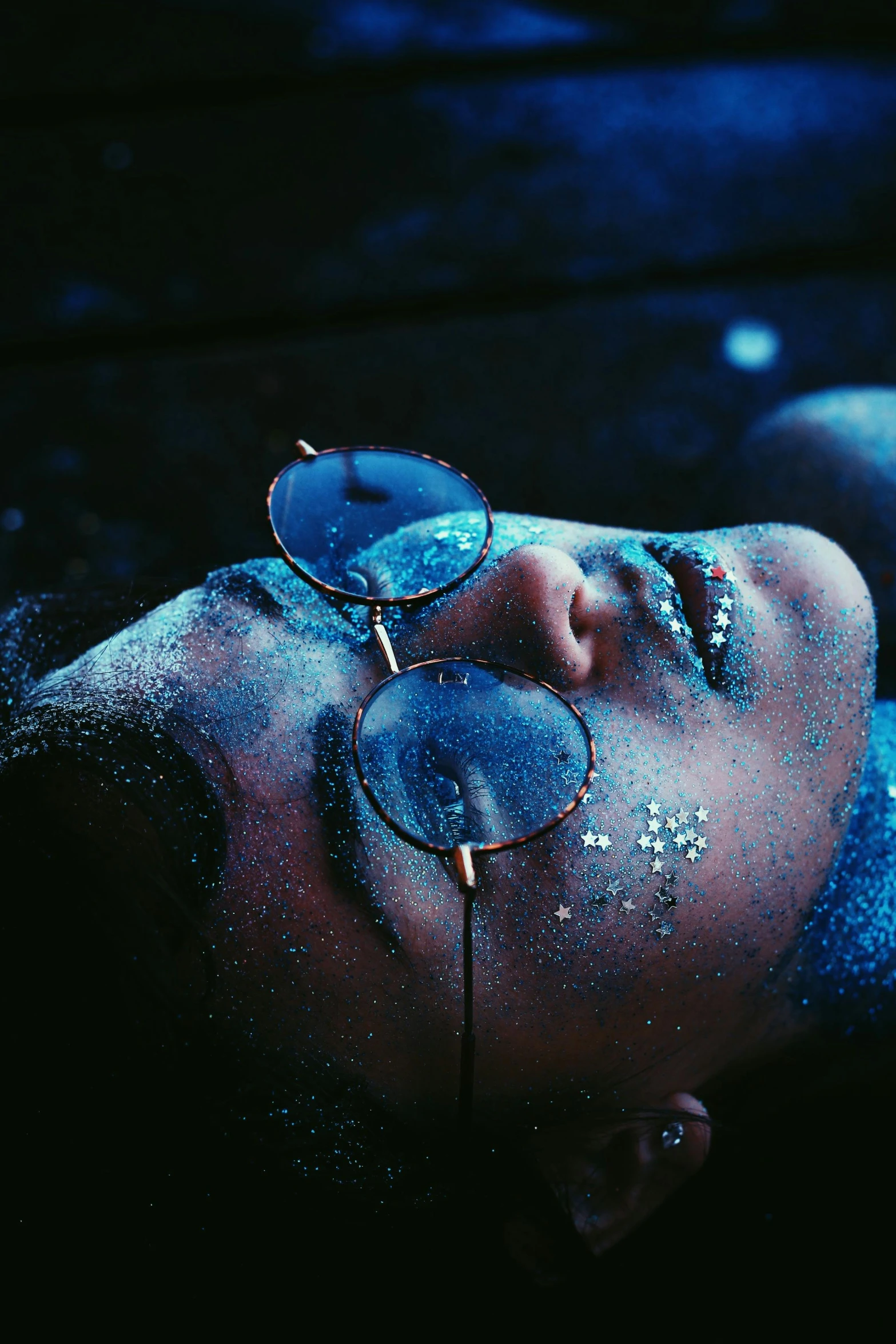 a woman wearing a mirrored sunglasses laying on the ground
