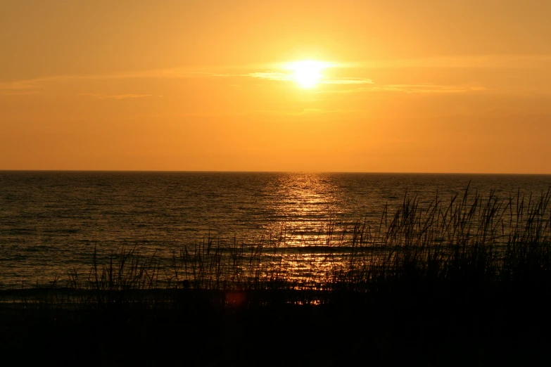 the sun setting on the horizon behind the water