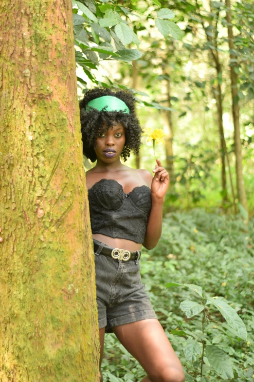 a woman wearing a short skirt stands in the forest with a tree