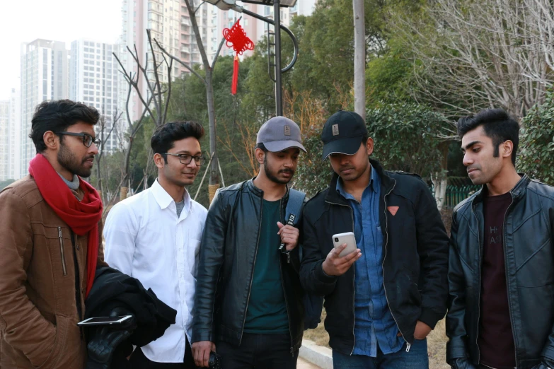 a group of men standing in a street holding their cell phones