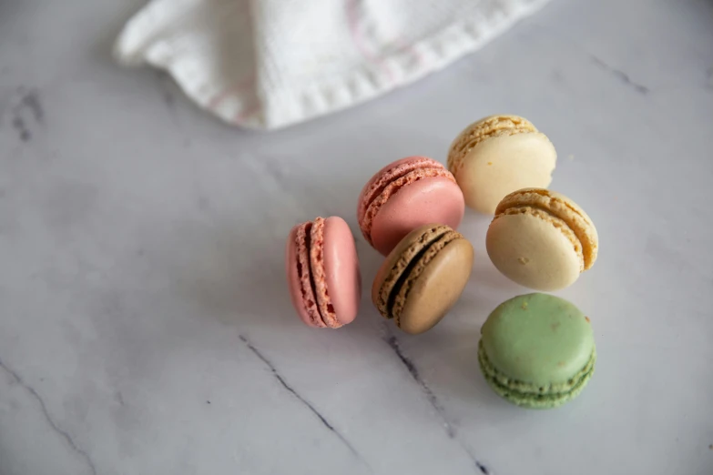 four small colorful macaroons are on a marble table