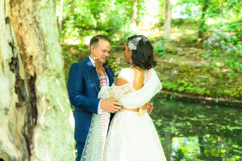 the bride and groom pose for pictures by a pond