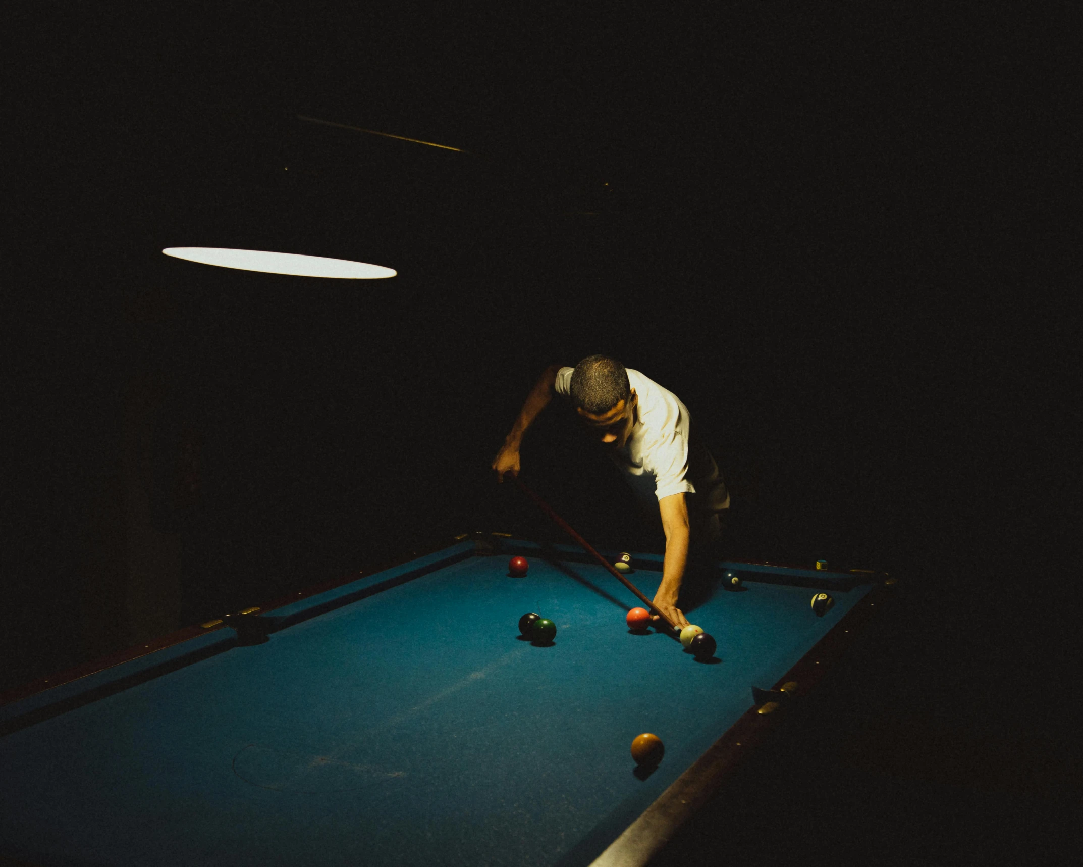 the man is playing billiard in a dark room