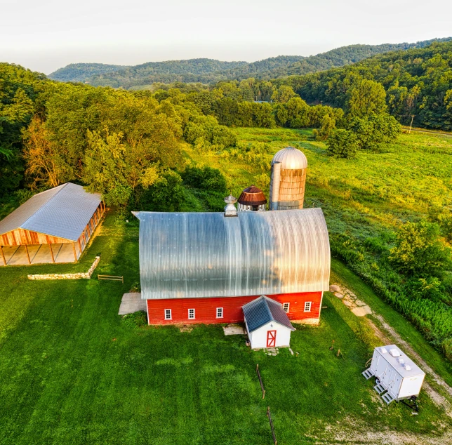 an aerial view of farm buildings and surrounding trees