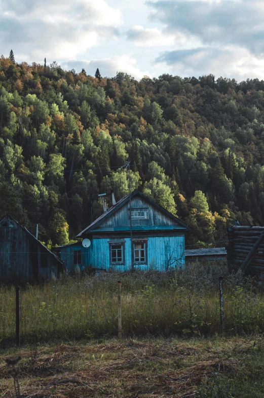 an old blue barn sitting next to a mountain