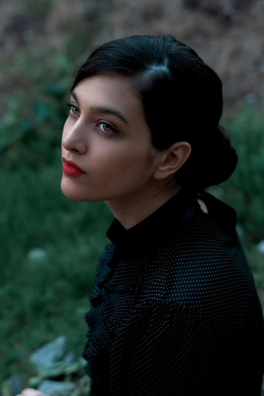 a woman looking off to the side, in a black dress and red lipstick