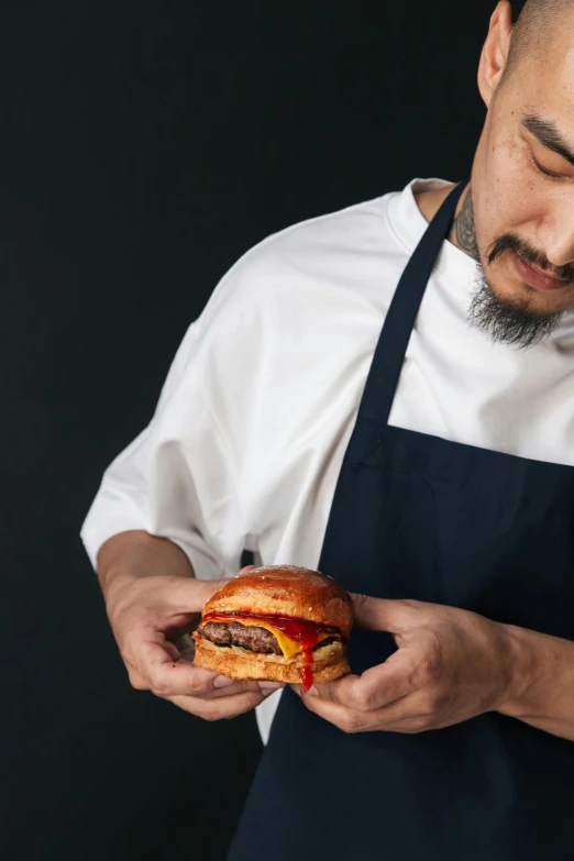 a man wearing an apron holds a sandwich