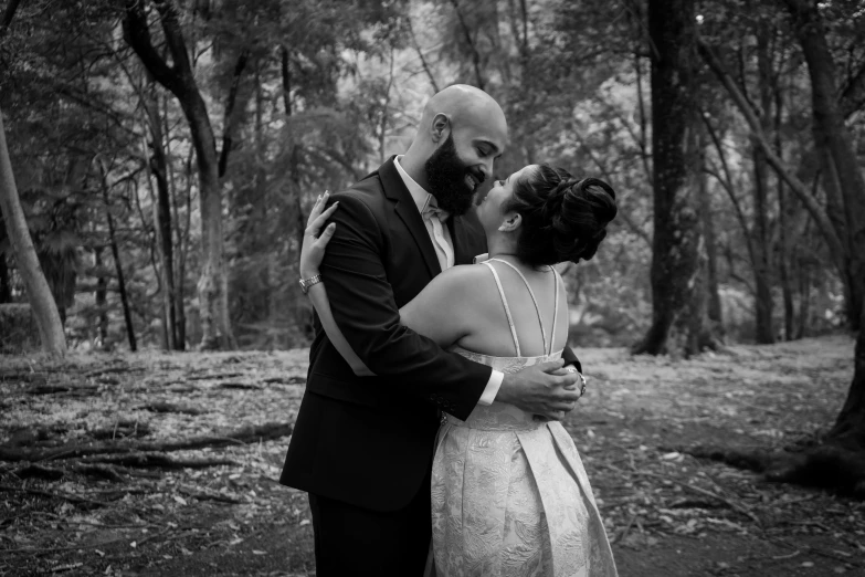 a man and a woman emcing while standing together in the woods