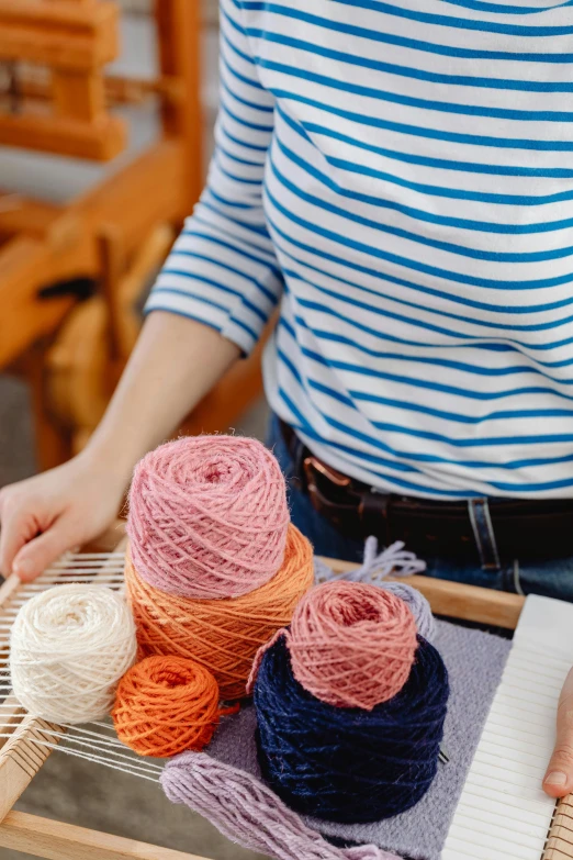 someone uses a yarn loom to make knitted scarves