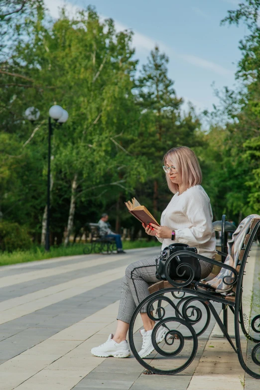 a women sits on a bench with a book in her hand