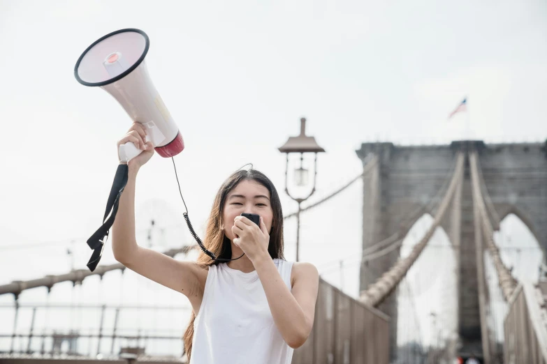 a woman using a megaphone in the middle of a bridge