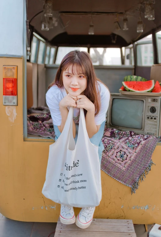 a girl sitting on top of a pile of bags in front of a bus