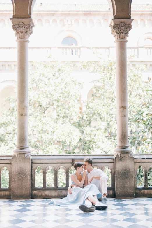 two young people sitting on a marble balcony together