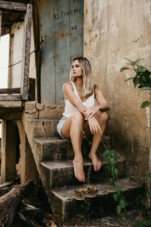 a beautiful woman sitting on top of some stone stairs
