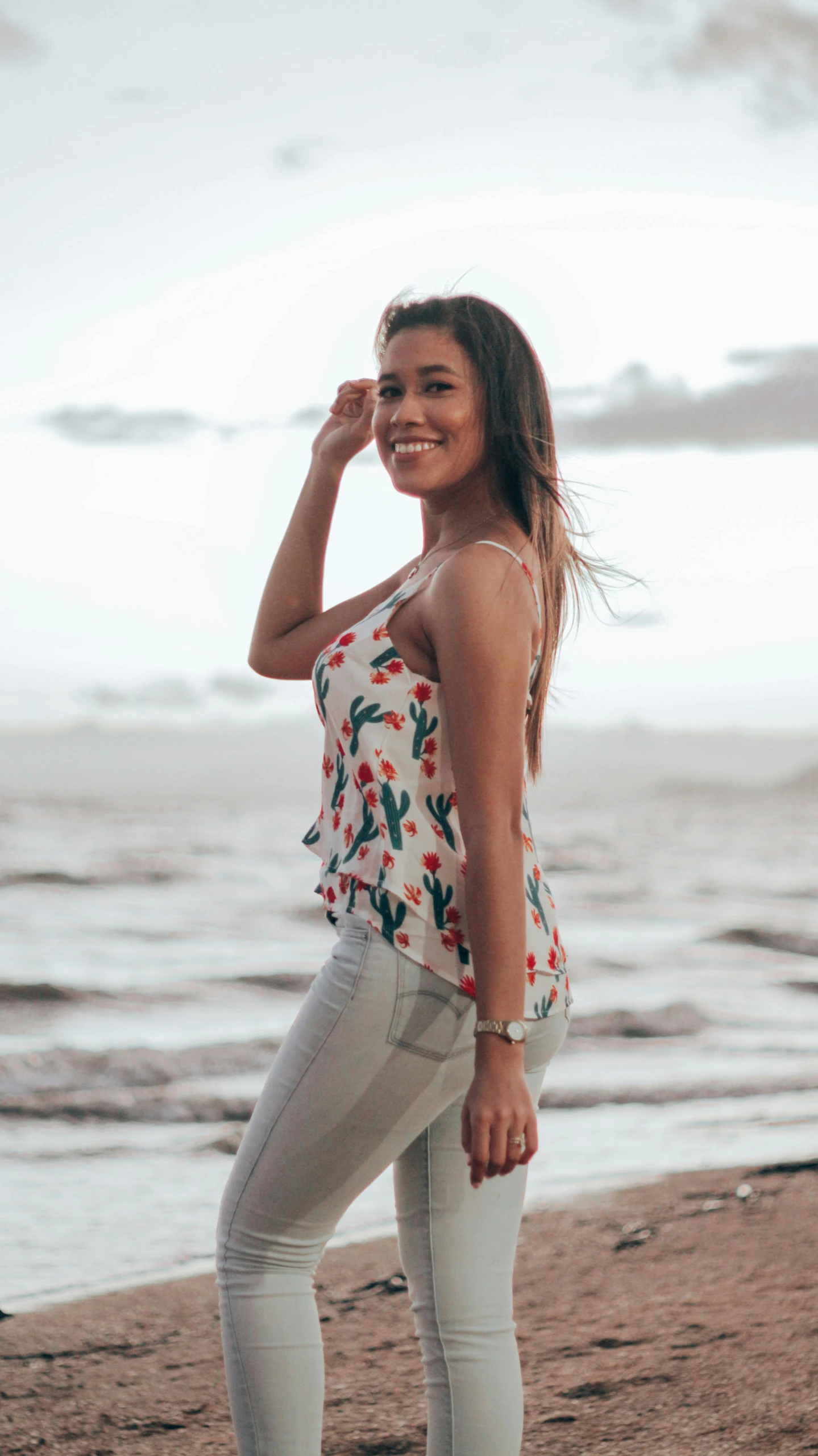 a woman standing on the sand by the ocean