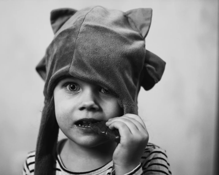 small child dressed in striped shirt and cap holding a spoon