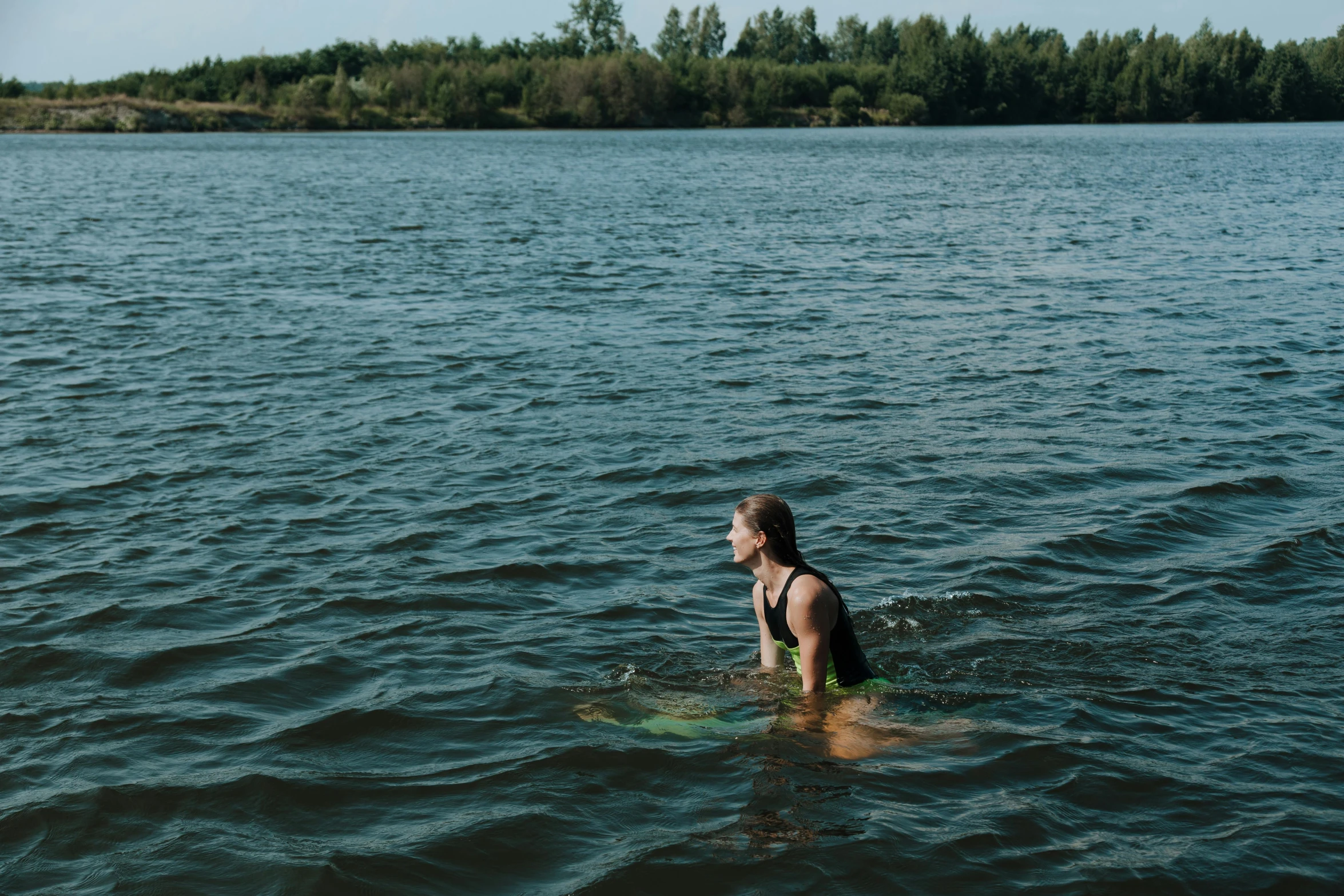 a woman is standing in the water near a island