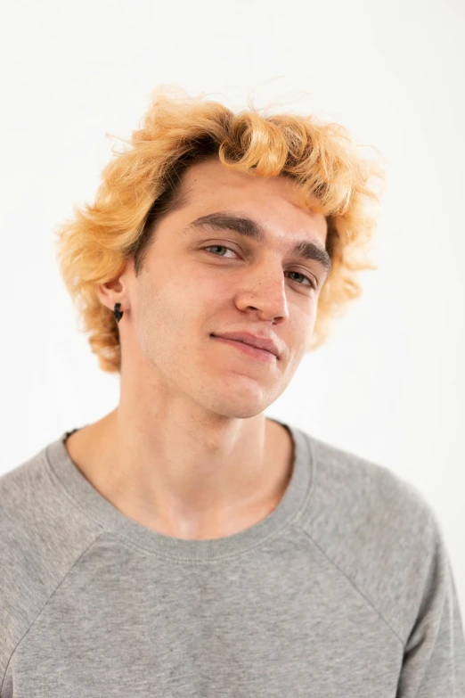 young man with bright yellow hair and gray shirt looking away