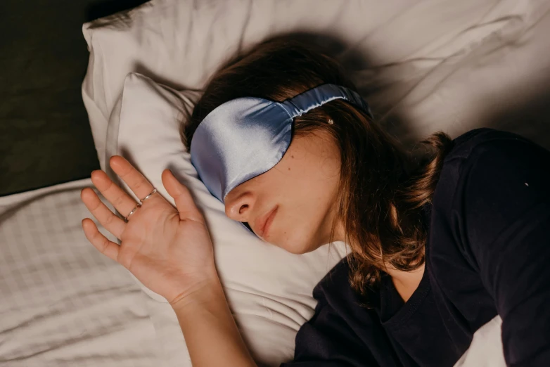 the girl is laying in bed with a blindfold