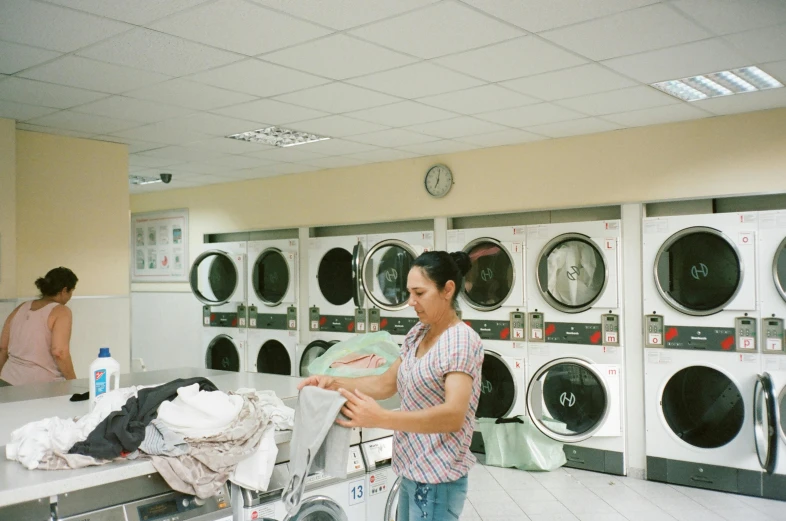 a man that is loading a dryer with clothes