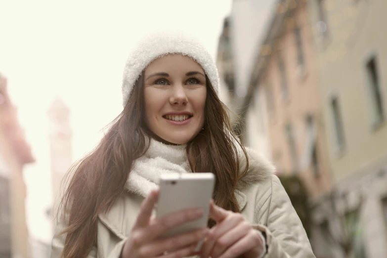 a smiling woman checks her phone while walking down the street