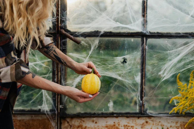 a woman holding up a squash in front of some windows