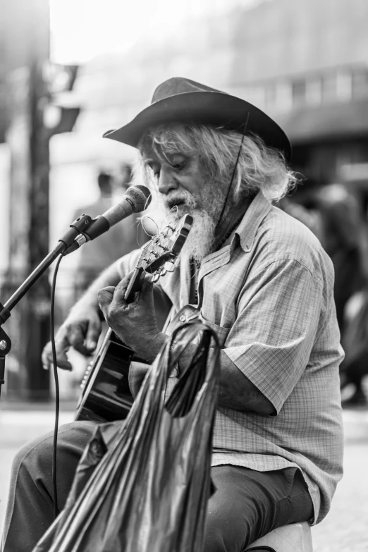 a man in a cowboy hat sitting on the ground playing a guitar