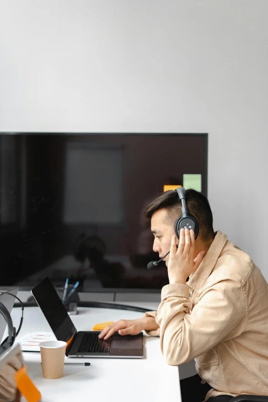man with headphones sitting at desk using laptop