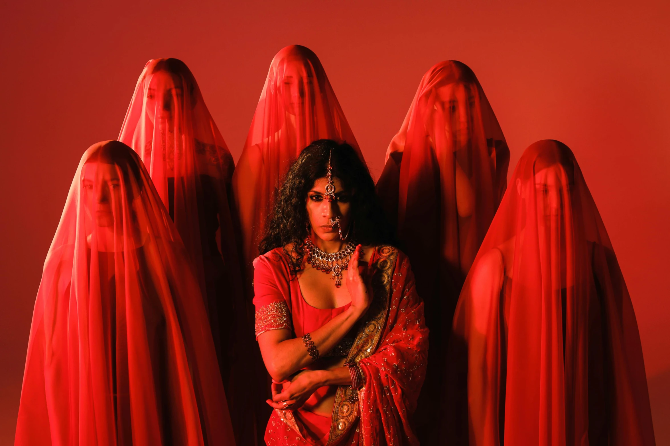 a woman in red sari sitting next to red sculptures