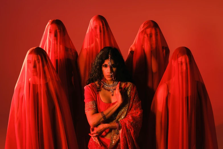 a woman in red sari sitting next to red sculptures