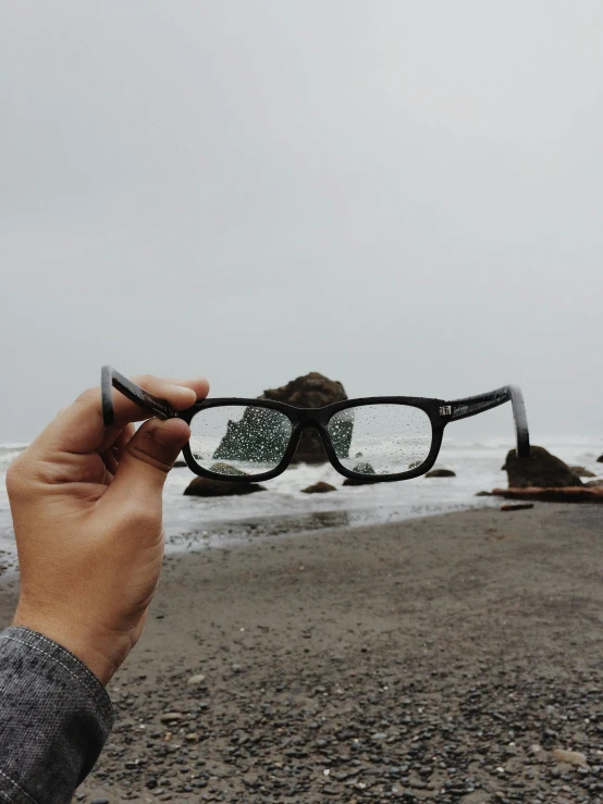 someone holding up a pair of glasses to see the ocean