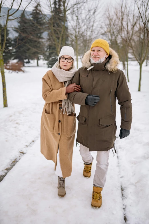 an older man and young woman walking in the snow