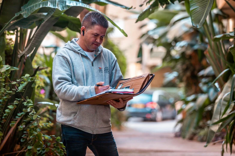 a man holding a book with his hand is looking down