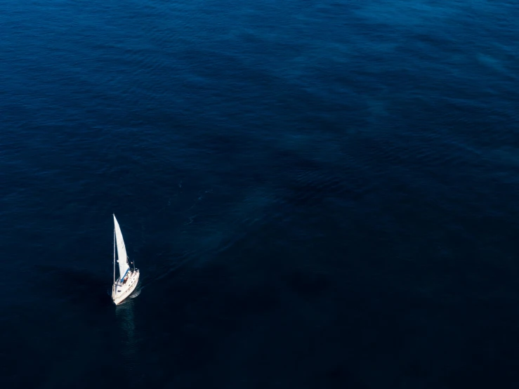 a lone sailboat on the ocean with only one sail