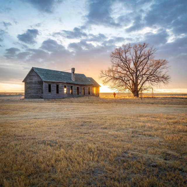 an empty barn sits in a wide open field