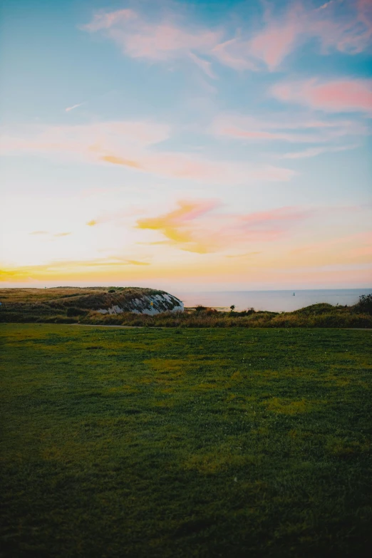 a field with the sun in the distance