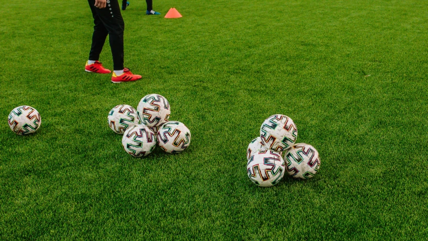 five soccer balls and people in the grass