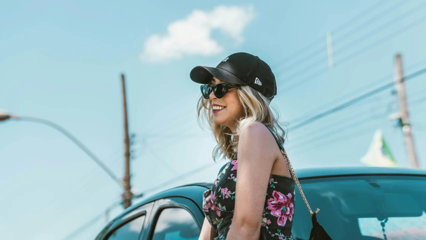 woman wearing sunglasses, flower print dress and black hat