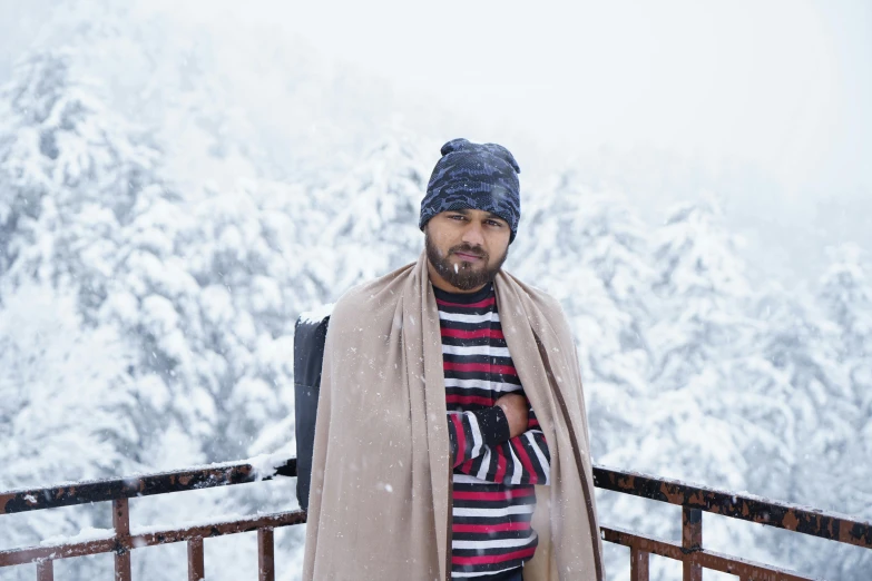 a man in a scarf and a hat poses for a picture