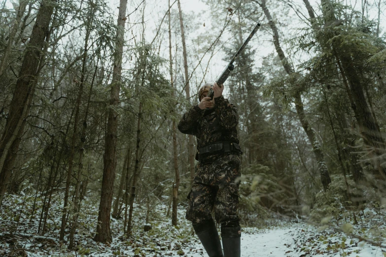 a man standing in the snow holding a gun