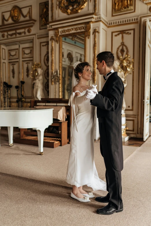 a bride and groom standing next to each other in front of a white piano