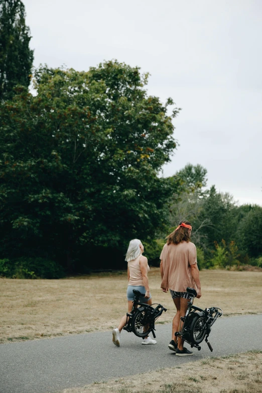 two women wearing pink outfits ride bicycles down a path