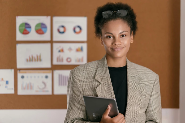 a woman wearing glasses and jacket holding an electronic device