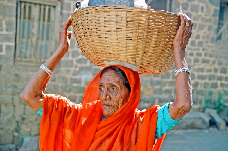 woman in sari carrying large basket over head