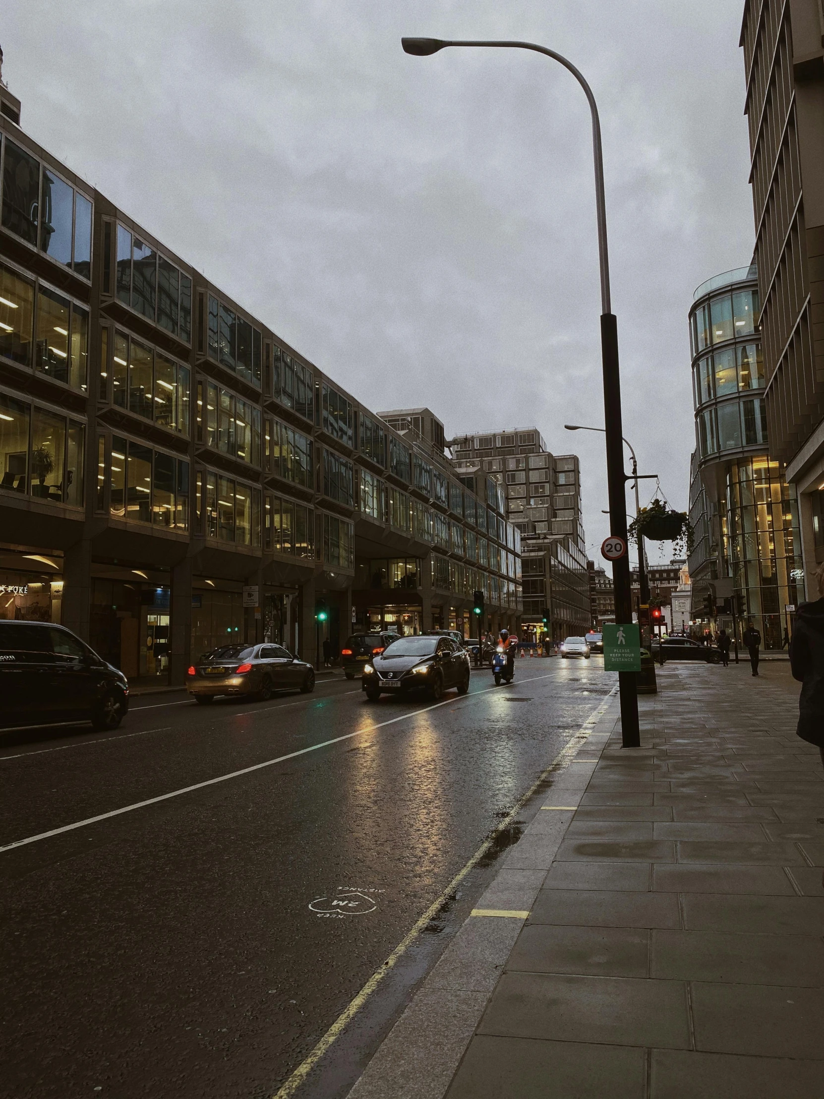 people are walking down a city street at dusk