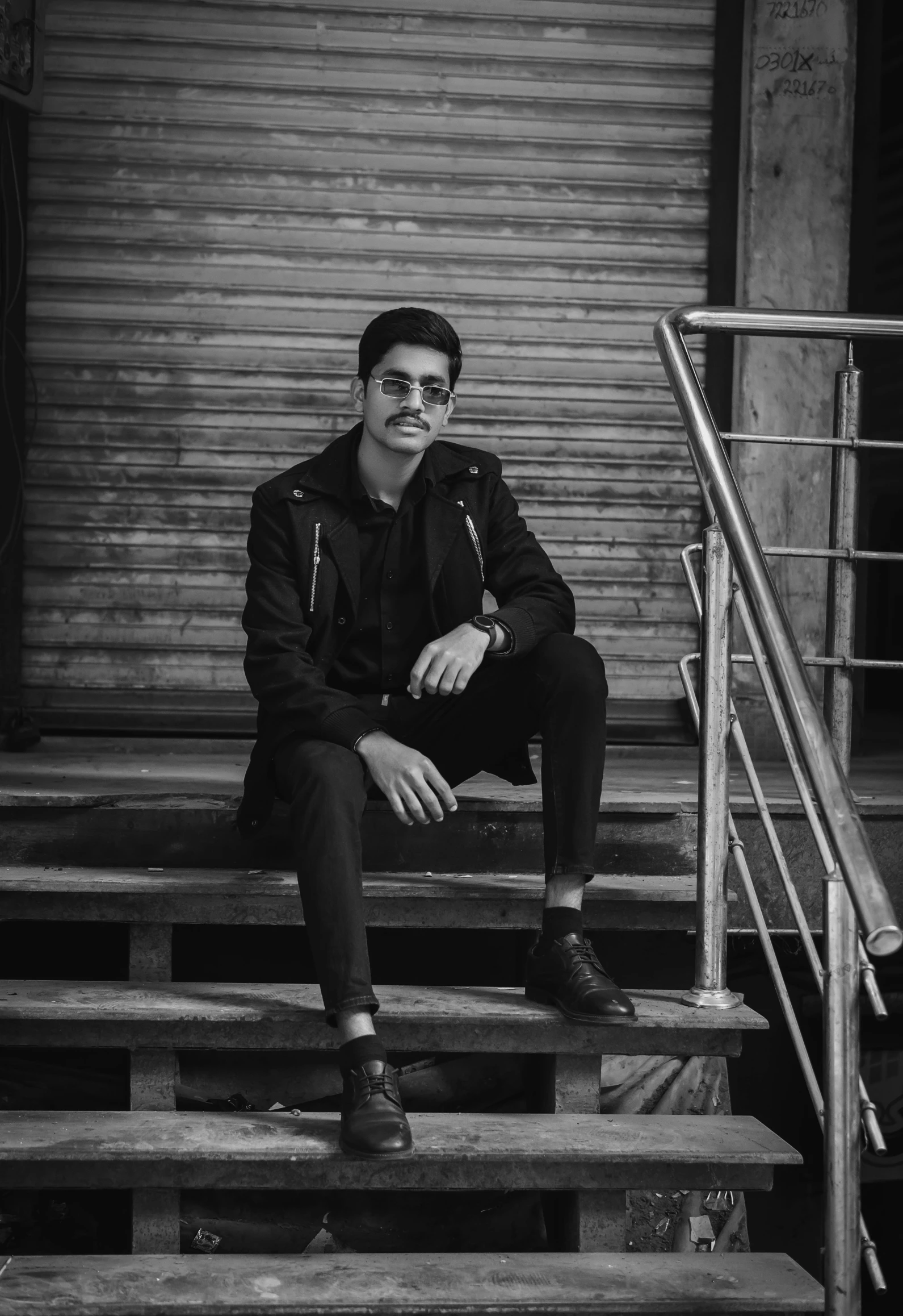 a young man with a jacket on sitting on the steps