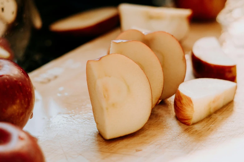 a wooden  board topped with slices of apple next to sliced apples